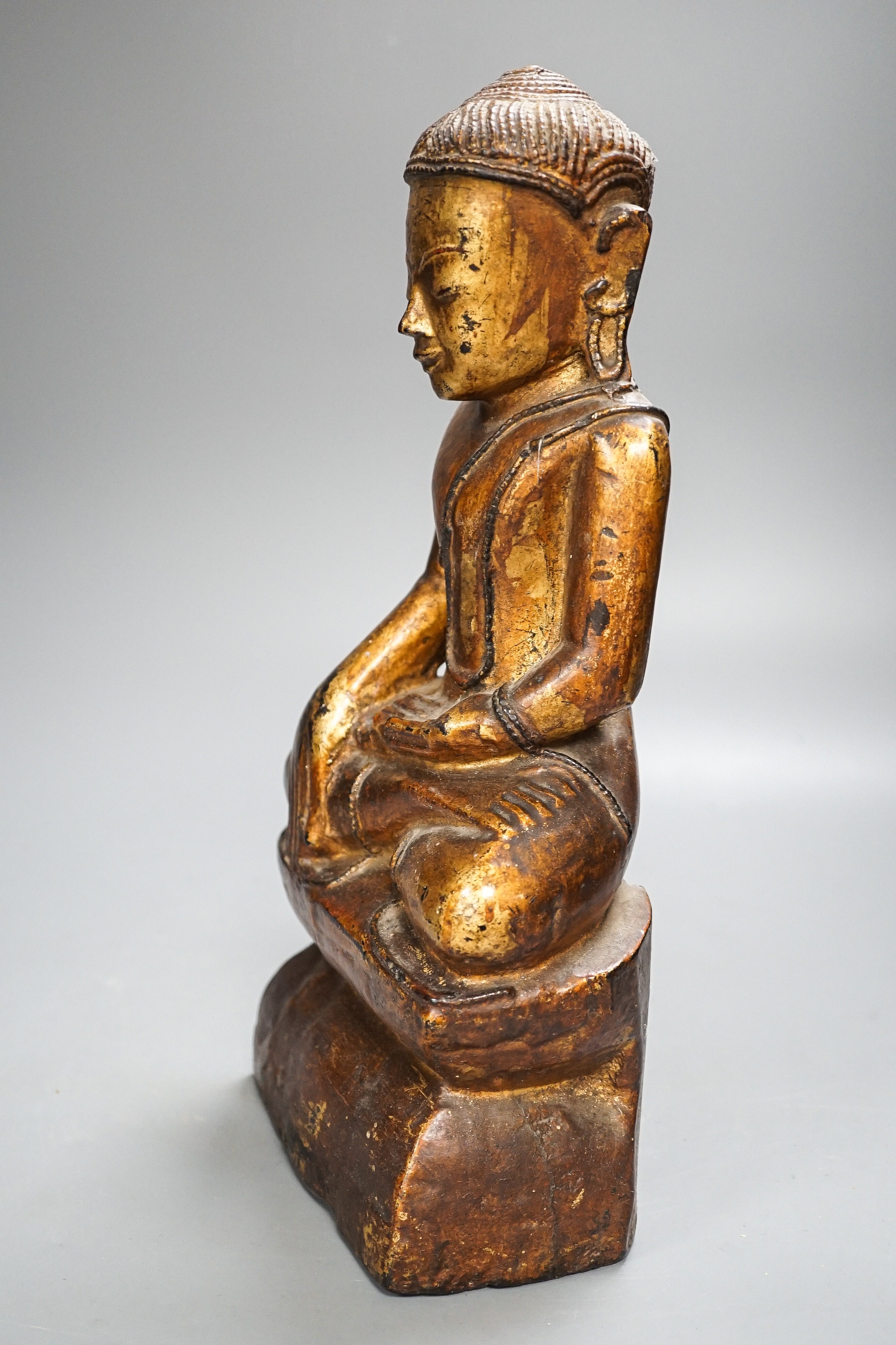 A Burmese gilded carved wooden figure of Buddha, 35 cms high.